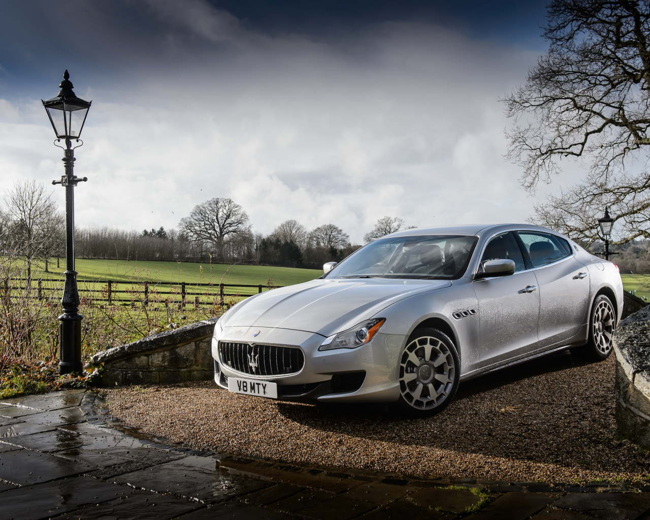 Серебристый стильный дорогой автомобиль Maserati Quattroporte на дороге после дождя