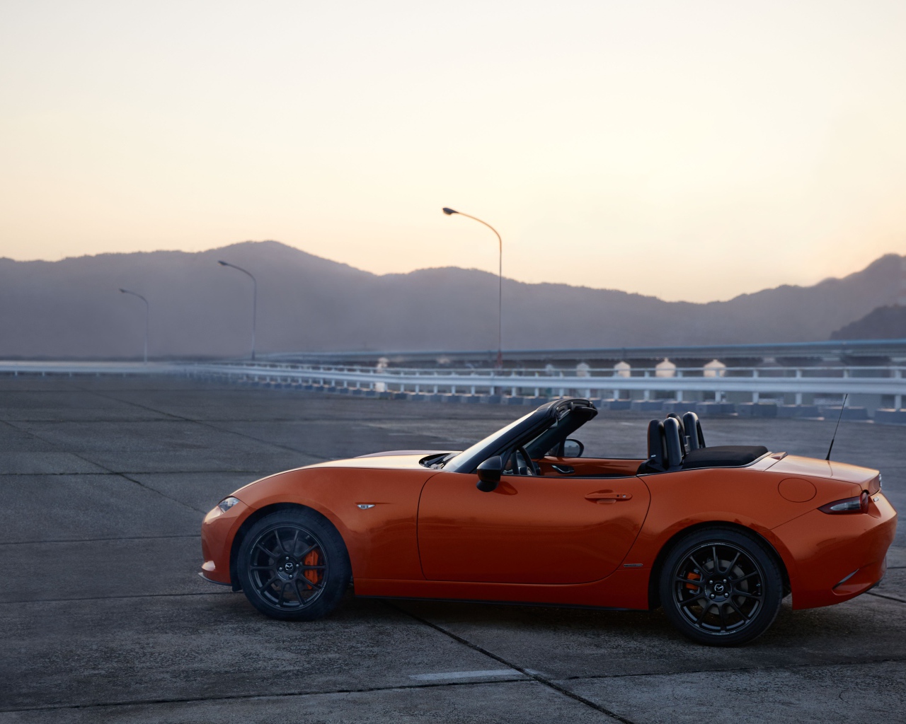 Оранжевый автомобиль кабриолет Mazda MX-5 на фоне неба