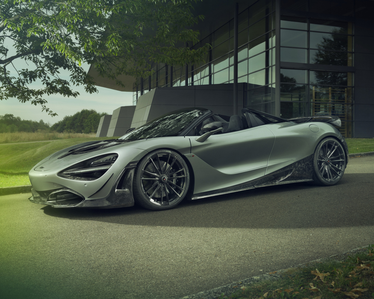 Серебристый автомобиль McLaren 720S Spider 2019 года у дома