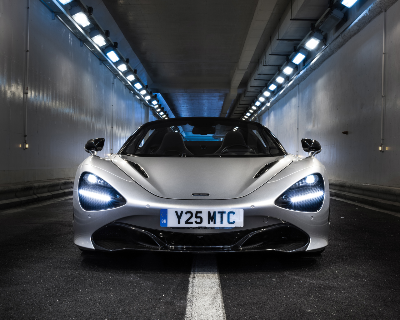 Серебристый спортивный автомобиль  McLaren 720S Spider, 2019 года в тоннеле