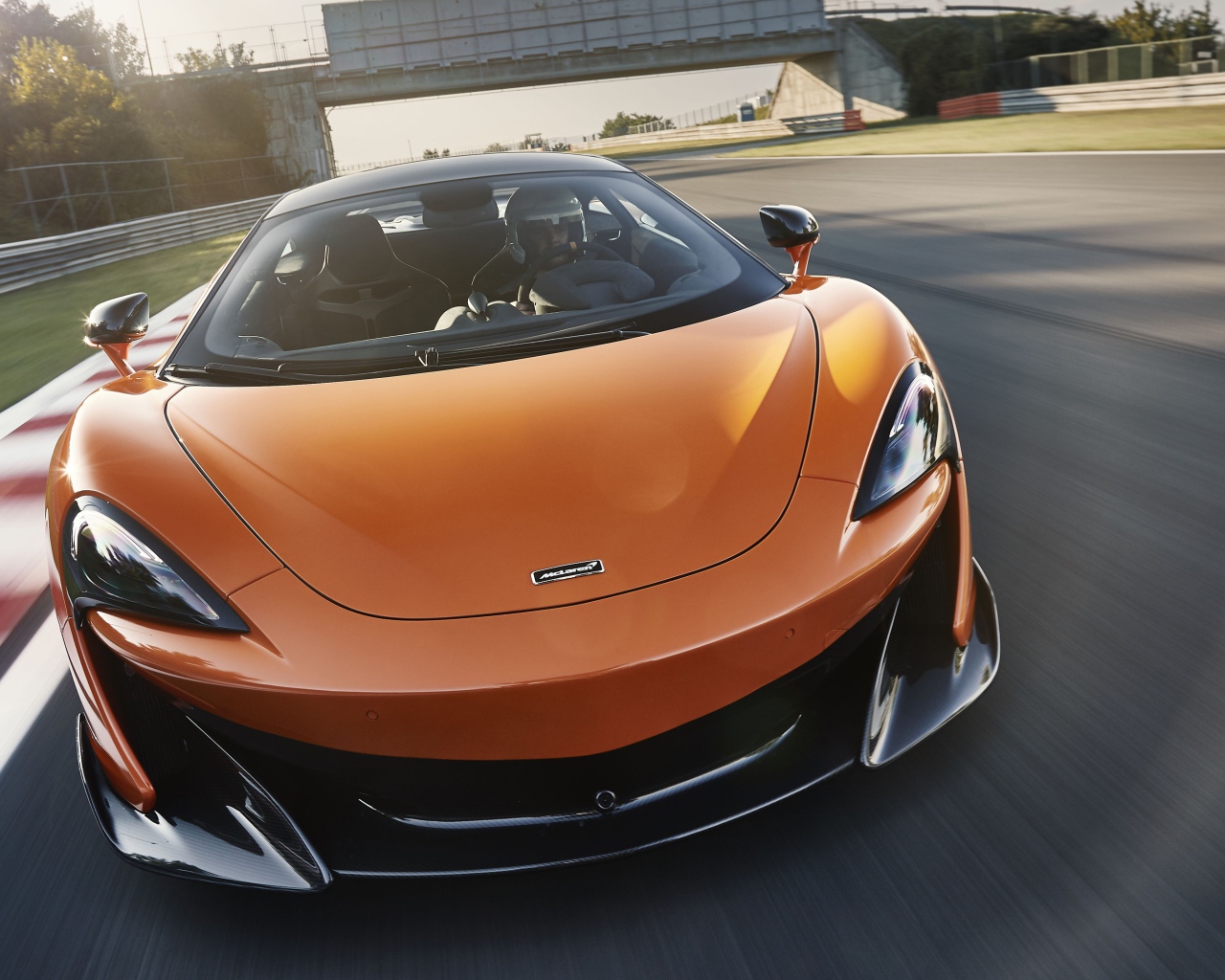 Спортивный оранжевый автомобиль McLaren 600LT 2019 года на трассе