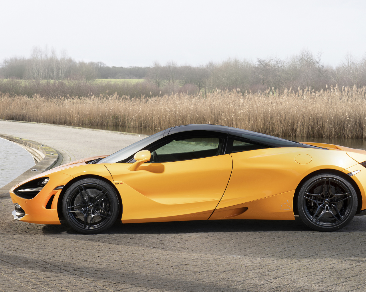 Желтый спортивный автомобиль McLaren MSO 720S Spa, 2019 года у воды