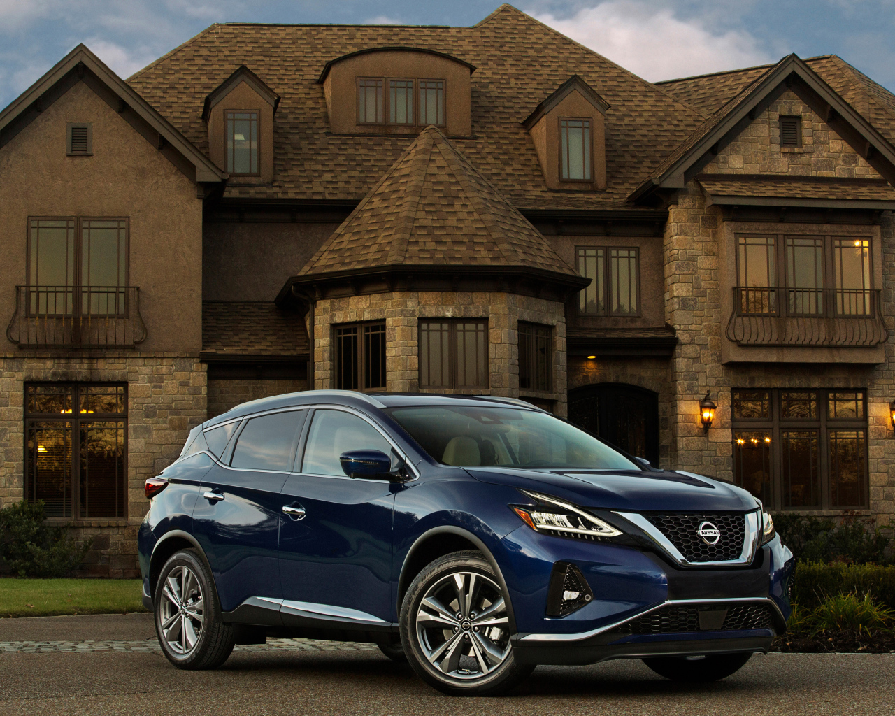 Синий автомобиль Nissan Murano на фоне особняка