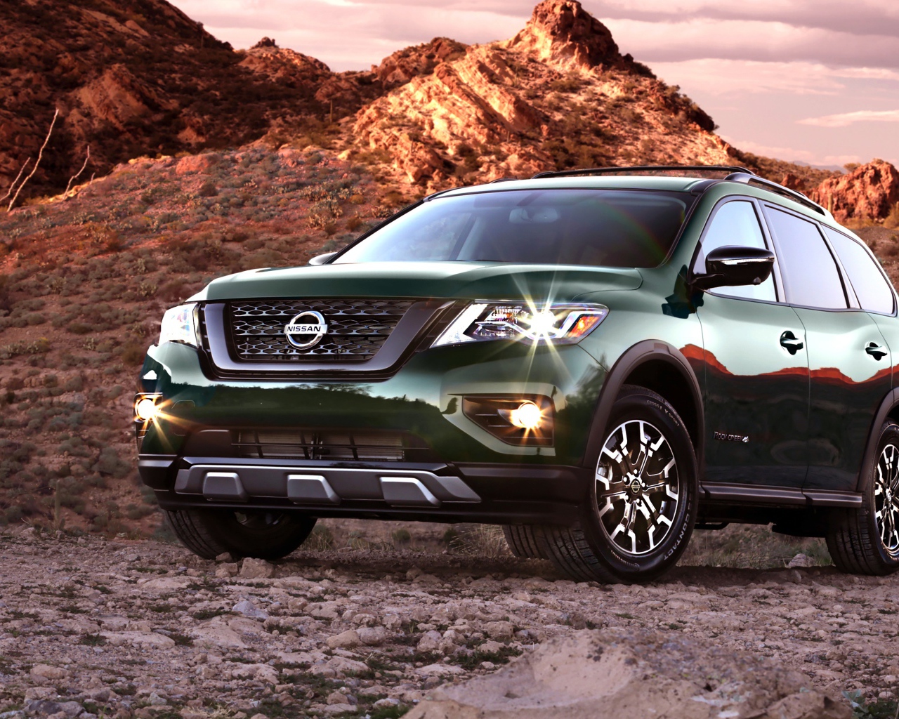 Зеленый автомобиль Nissan Pathfinder в горах 