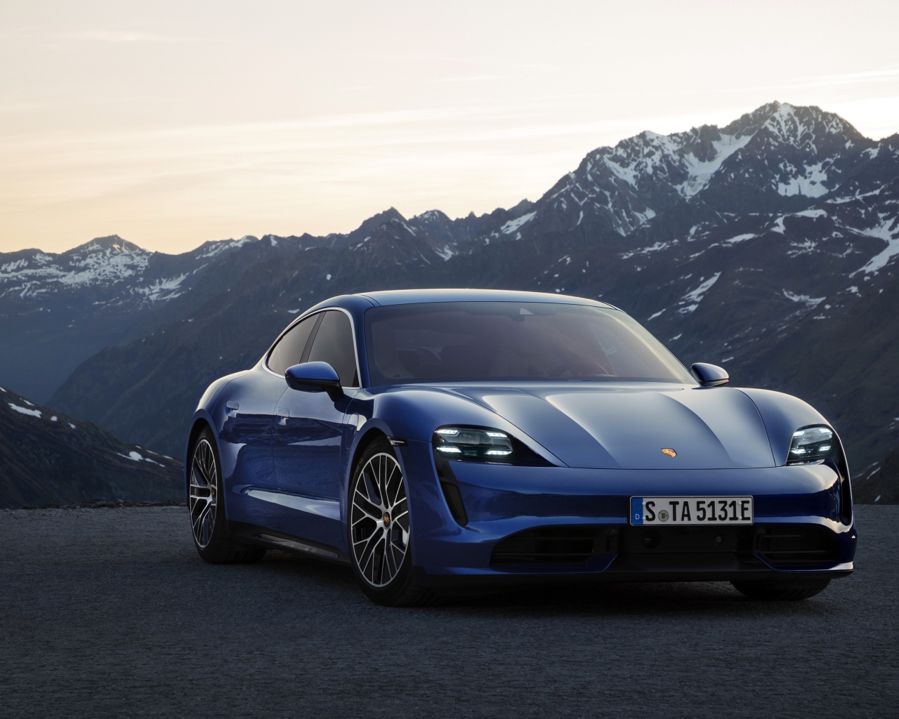 Синий стильный автомобиль Porsche Taycan Turbo 2019 года на фоне гор