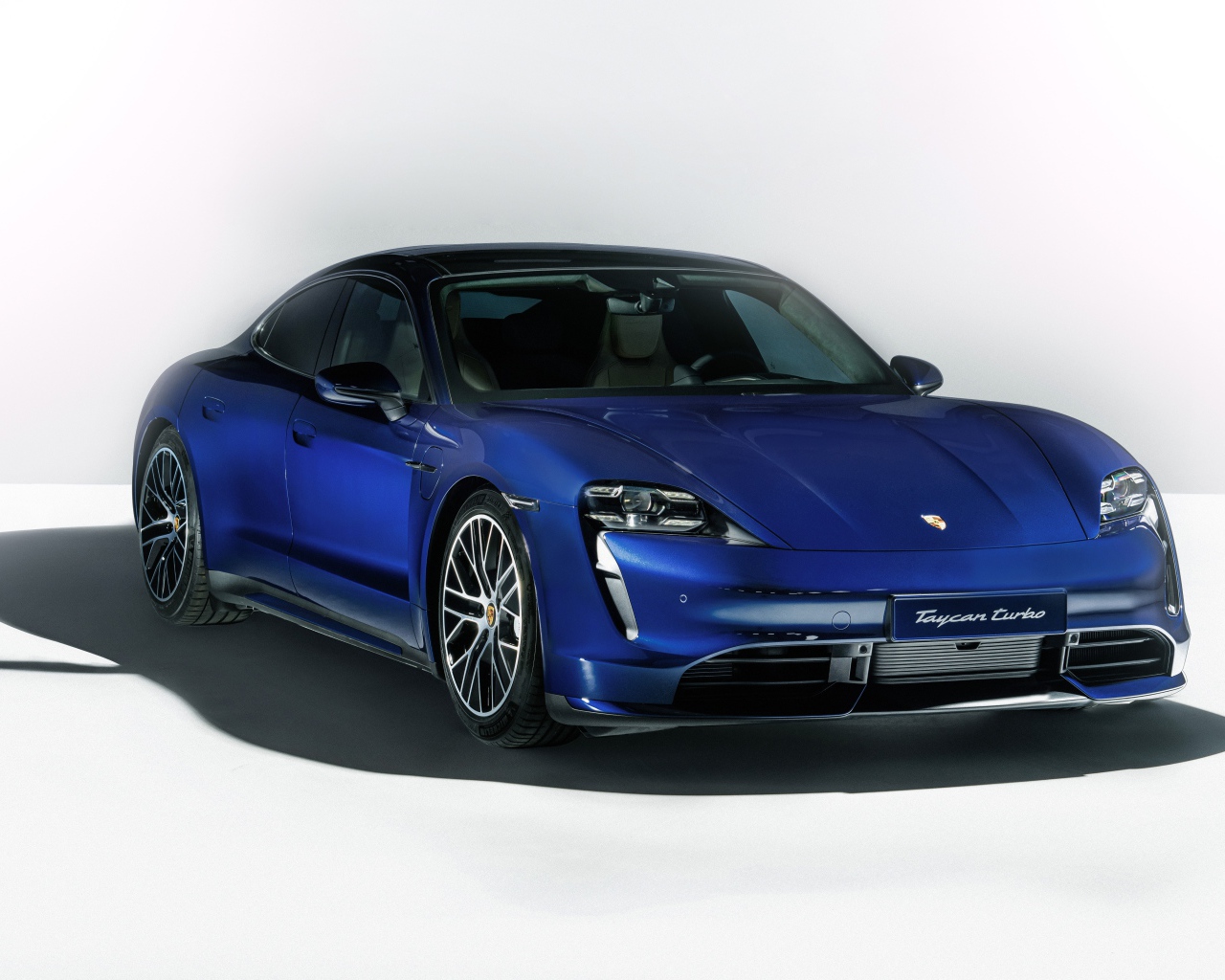Синий автомобиль Porsche Taycan Turbo 2019 года на сером фоне