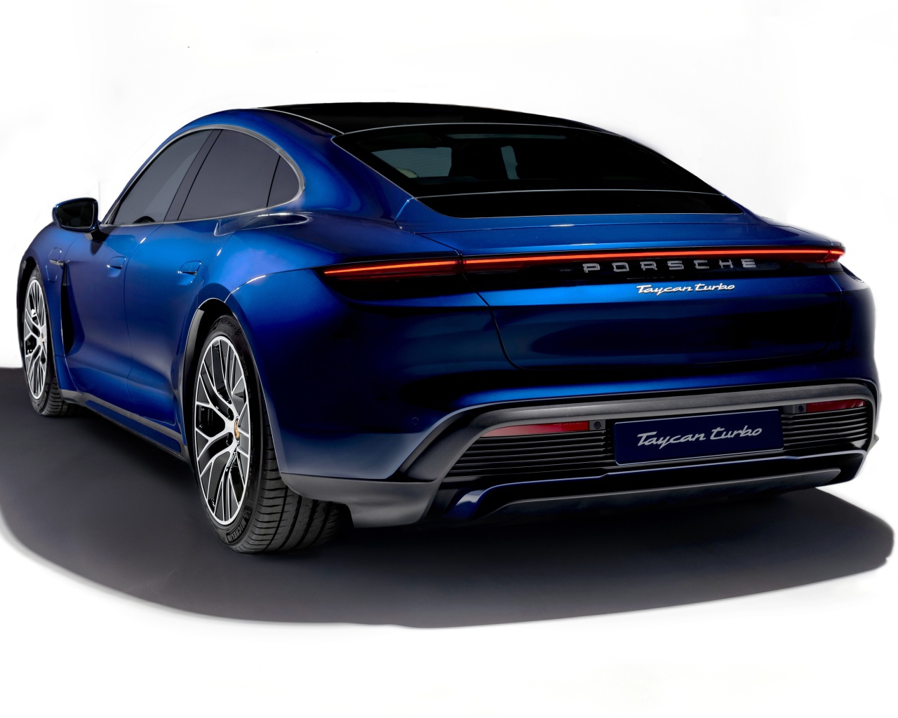 Синий автомобиль Porsche Taycan Turbo 2019 года на белом фоне