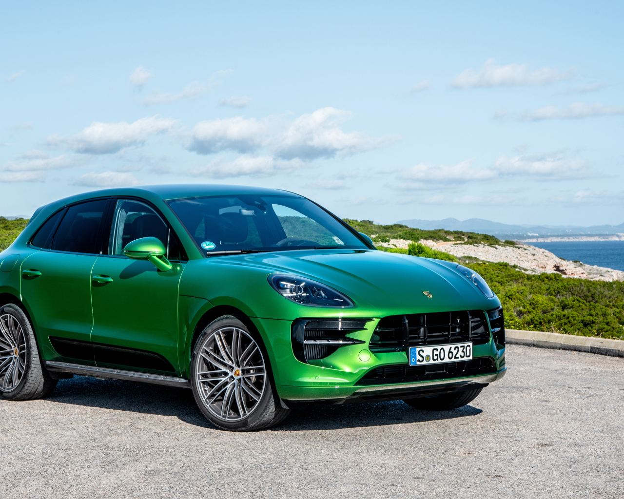 Зеленый внедорожник Porsche Macan S,  2018 года на фоне горизонта 