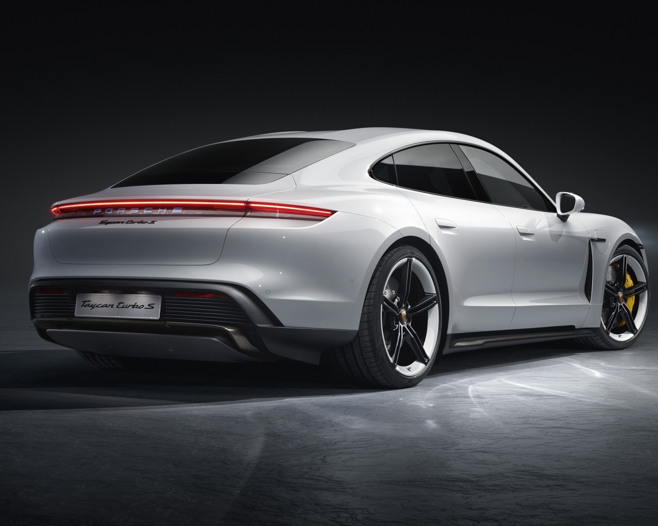 Серебристый автомобиль Porsche Taycan Turbo S 2019 года вид сзади