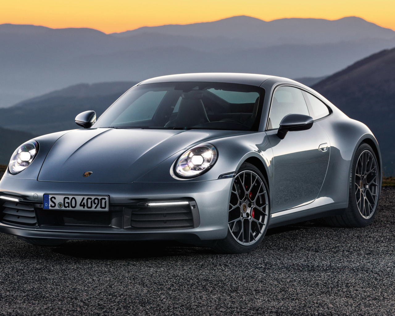 Серебристый автомобиль Porsche 911 Carrera 4S 2019 года на фоне гор 