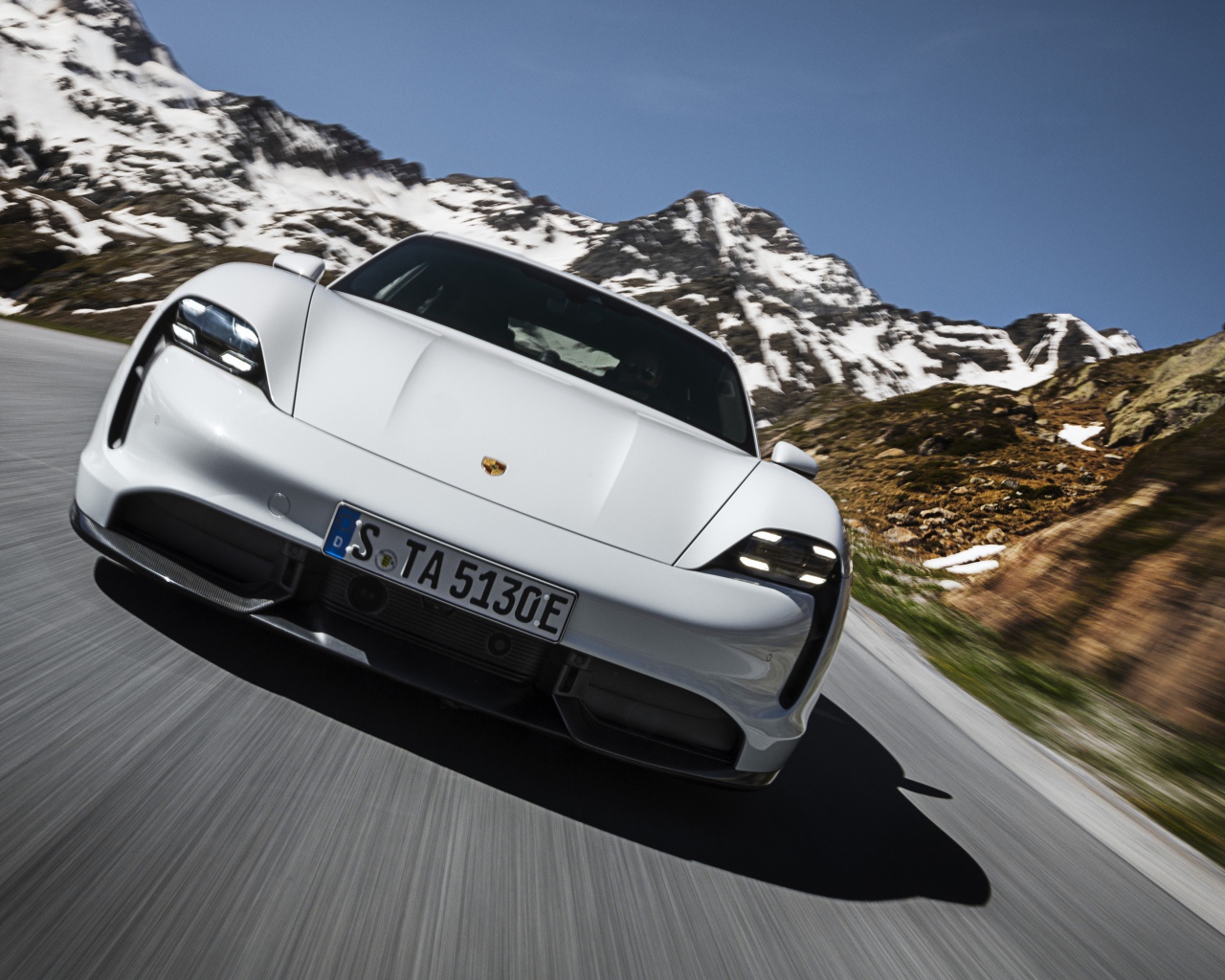 Белый автомобиль Porsche Taycan Turbo S 2019 года на фоне заснеженных гор