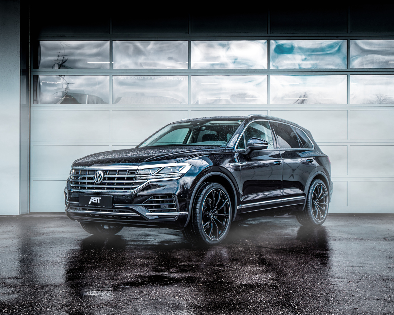 Черный автомобиль Volkswagen Touareg 2018 года у гаража