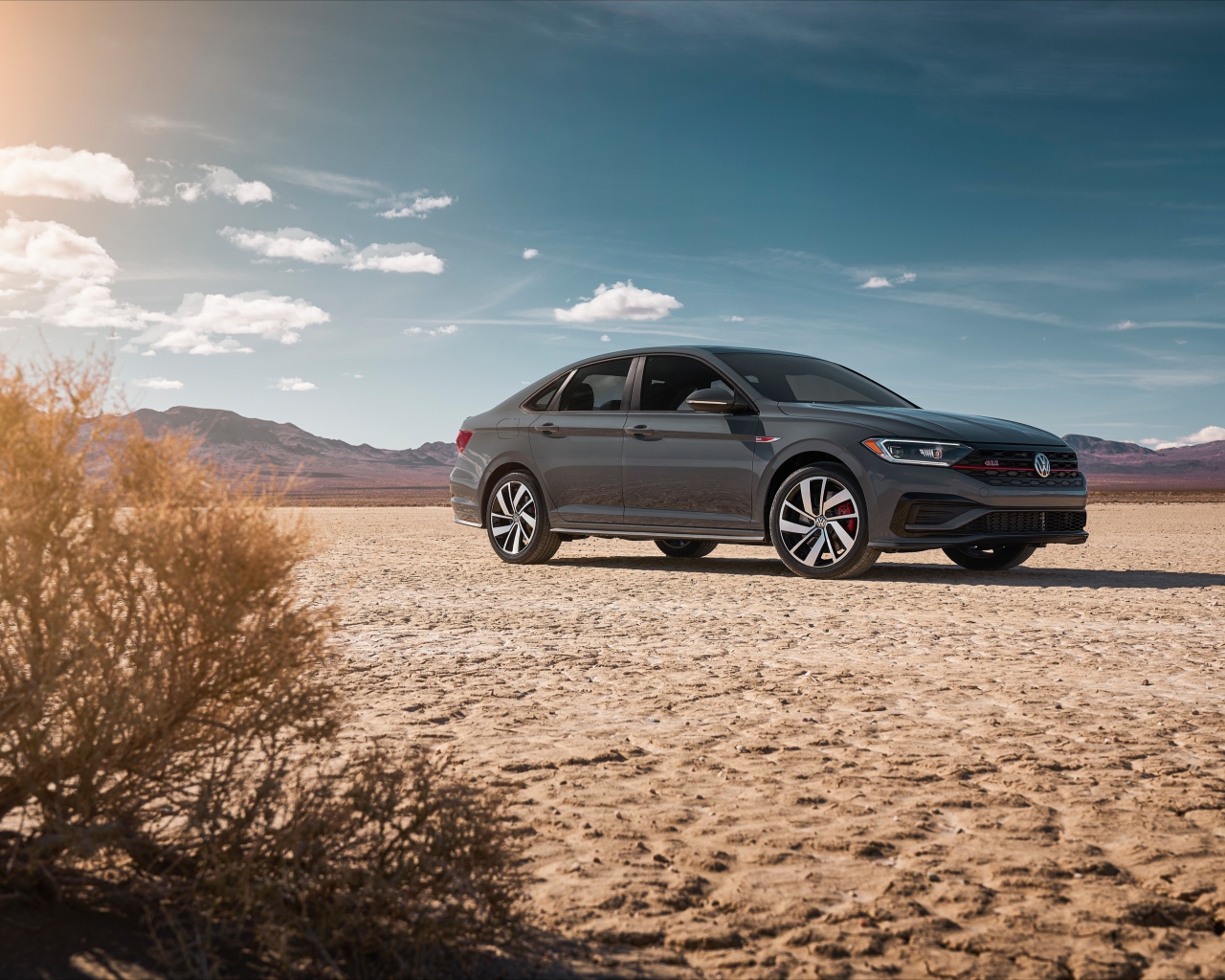 Стильный серебристый автомобиль Volkswagen Jetta на фоне неба 