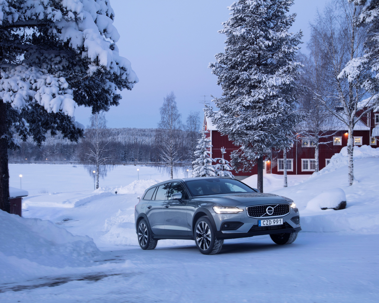 Автомобиль Volvo V60 на фоне заснеженных деревьев 