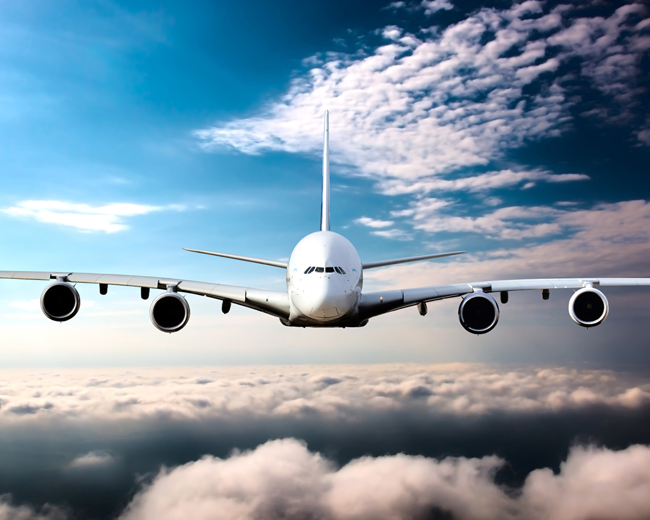 Самолет в белых облаках на фоне голубого неба