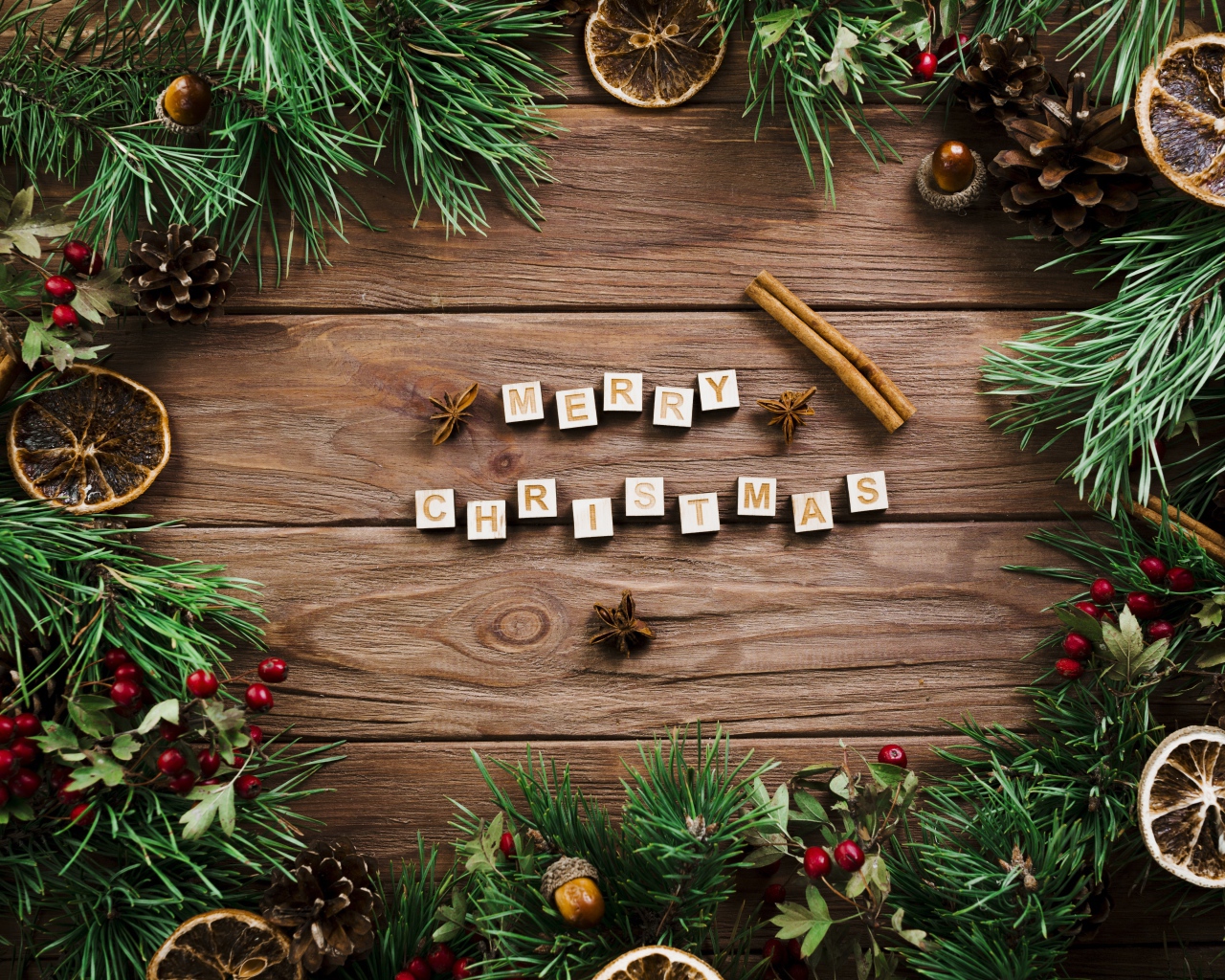 Надпись Merry Christmas на деревянном столе с еловыми ветками 