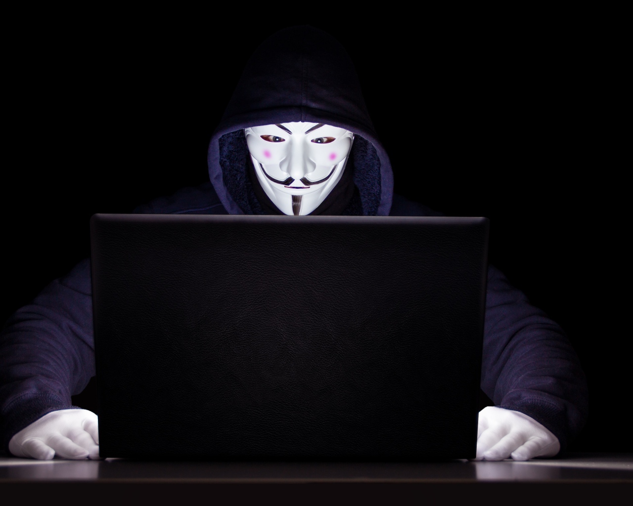 Хакер анонимус в маске и худи за ноутбуком