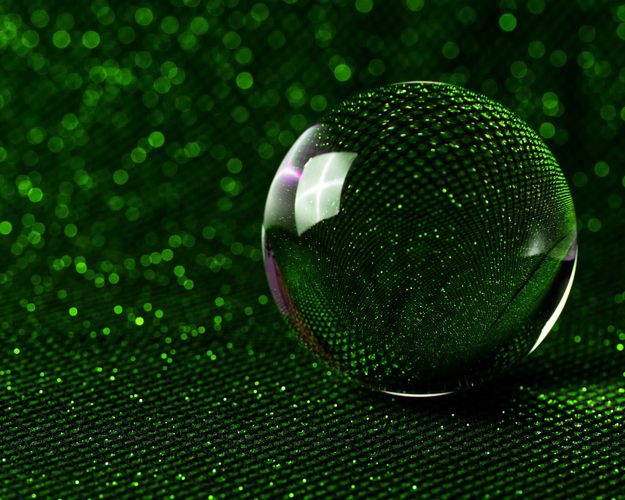 Большой стеклянный шар на зеленом блестящем фоне