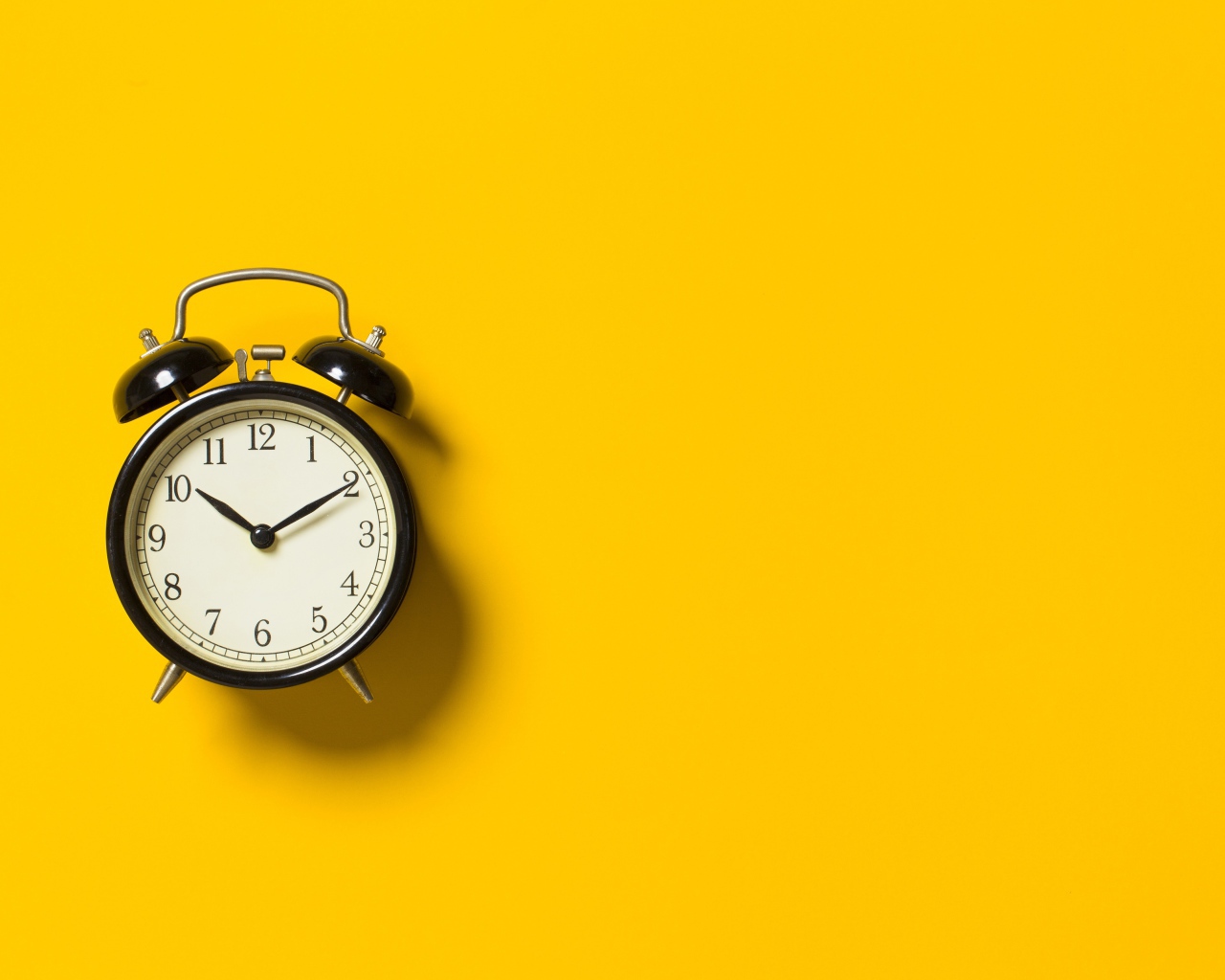 Черный будильник на желтом фоне