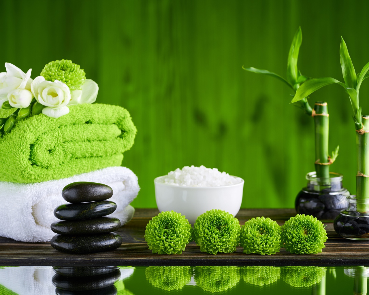 Черные камни, полотенца, соль и цветы у воды для SPA