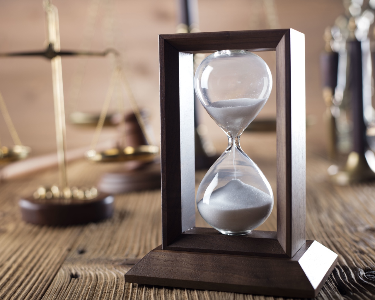 Песочные часы на столе с весами крупным планом