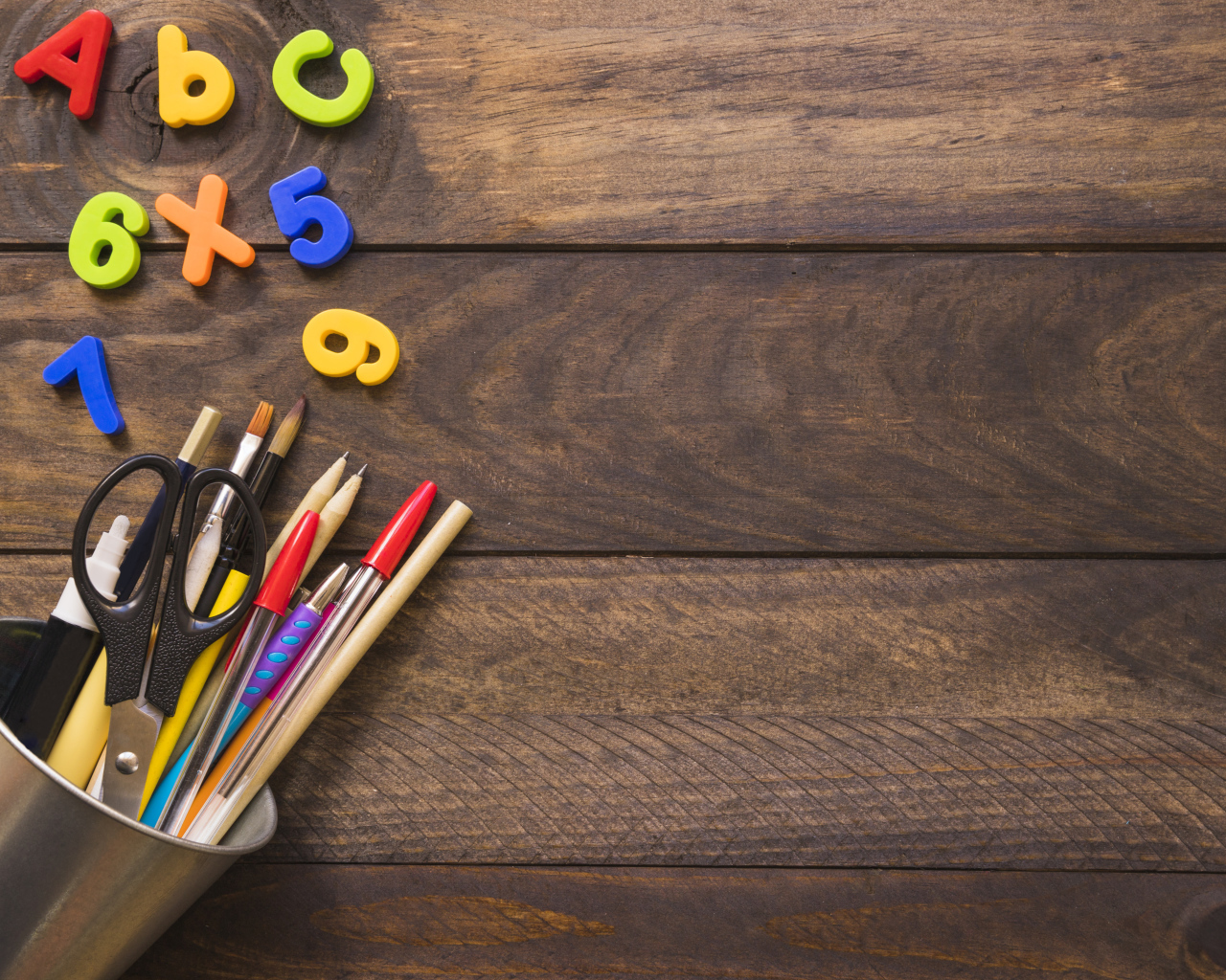 Банка с канцелярскими принадлежностями на деревянном столе с цифрами