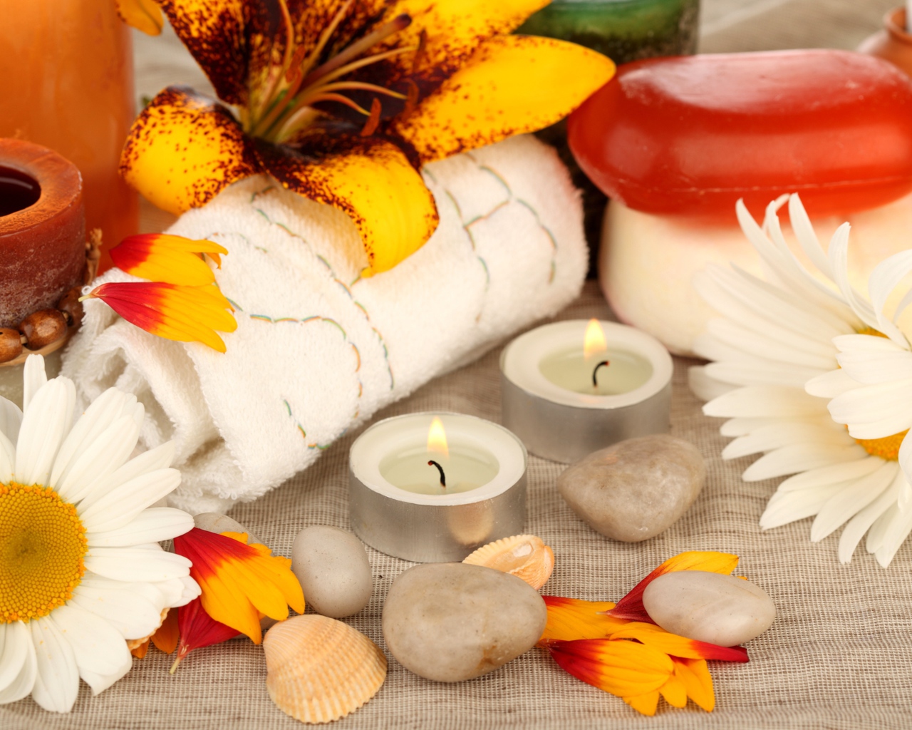 Зажженные свечи на столе с полотенцем, цветами и мылом