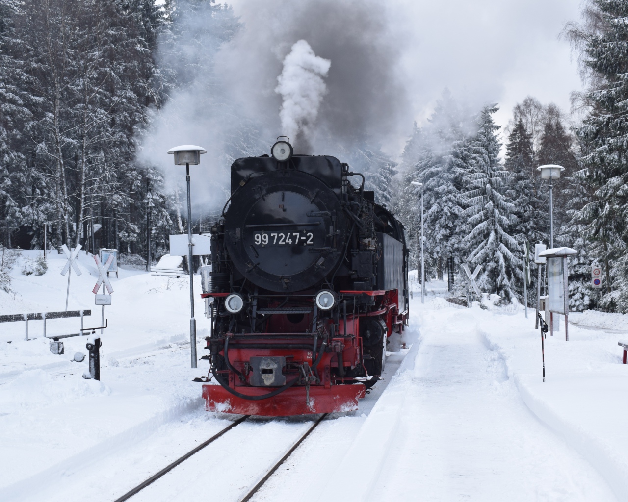 Старый локомотив на заснеженной станции у леса зимой