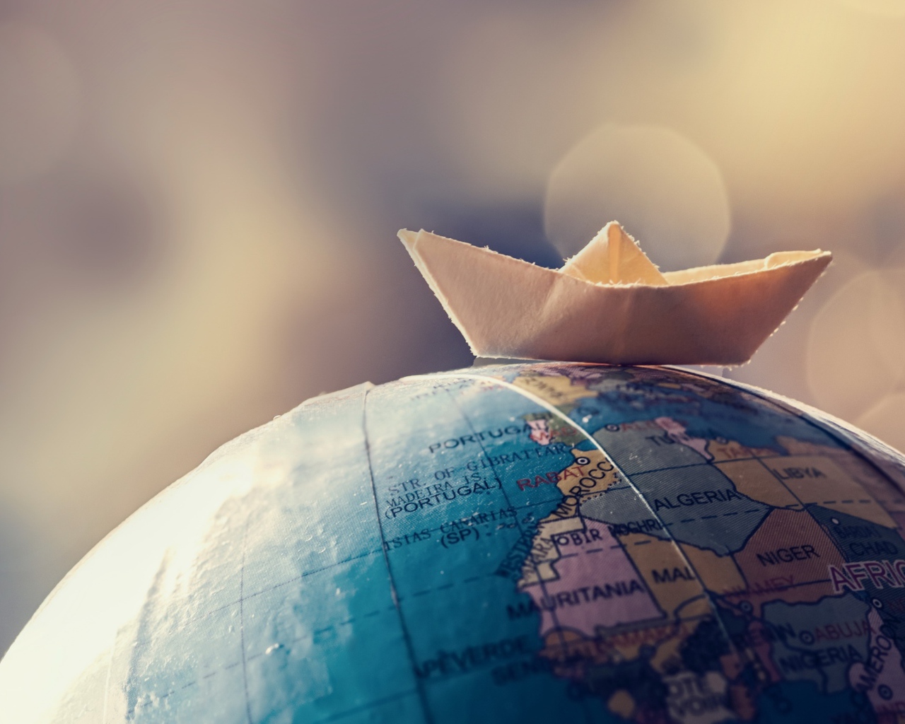 Бумажный кораблик лежит на глобусе