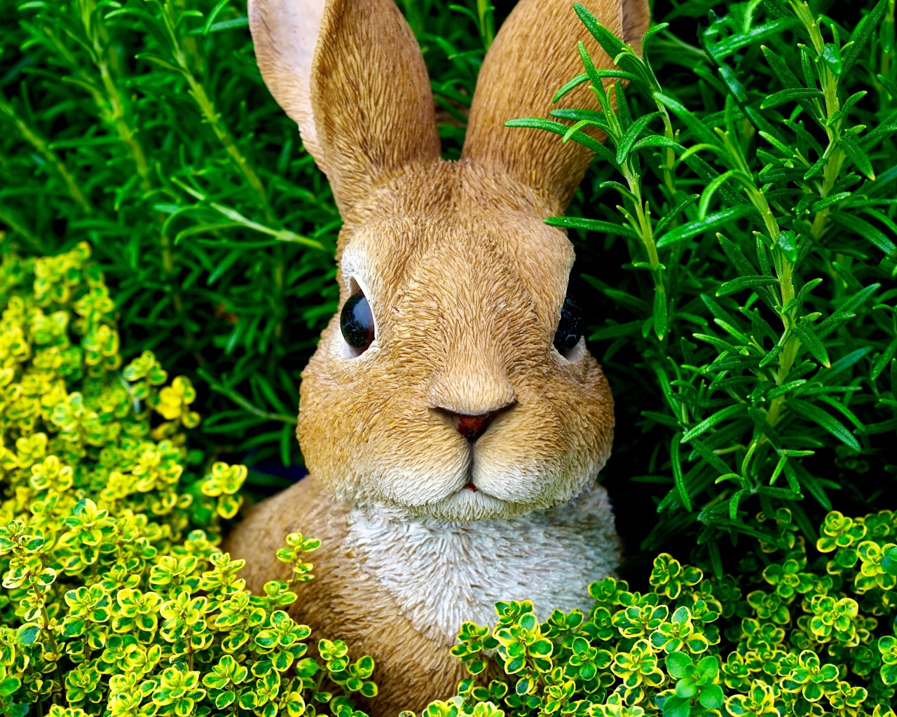 Статуэтка кролика в зеленой траве 
