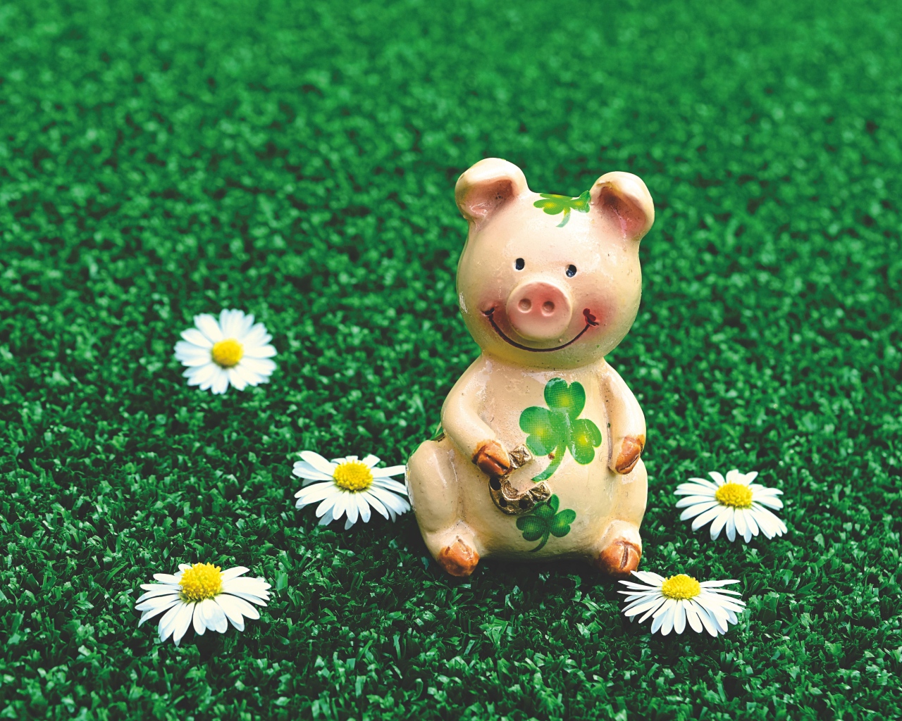Статуэтка поросенка на зеленой траве с ромашками