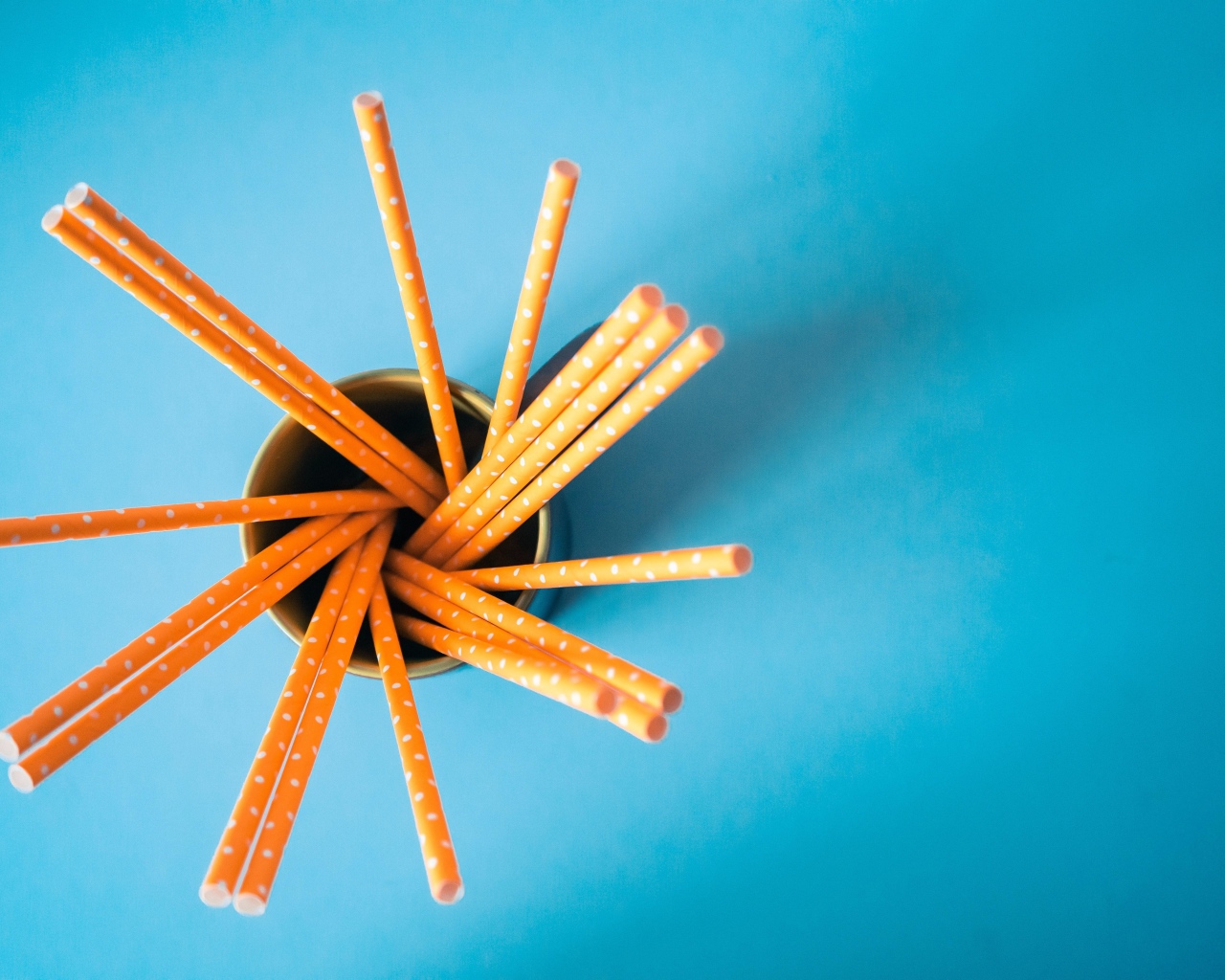 Трубочки в стакане на голубом столе