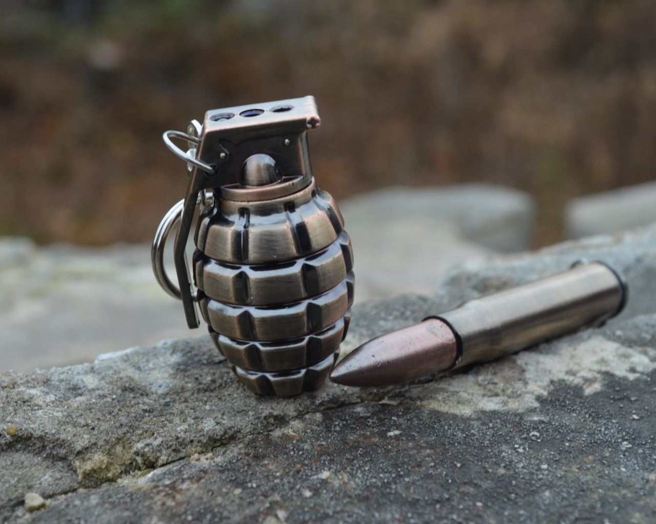 Боевая граната с патроном лежат на камне 