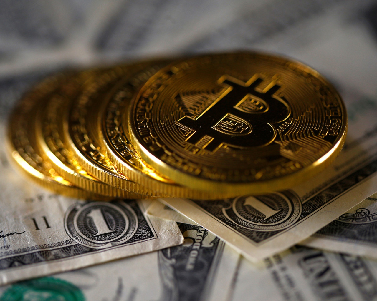Монеты Биткоин лежат на купюрах по одному доллару