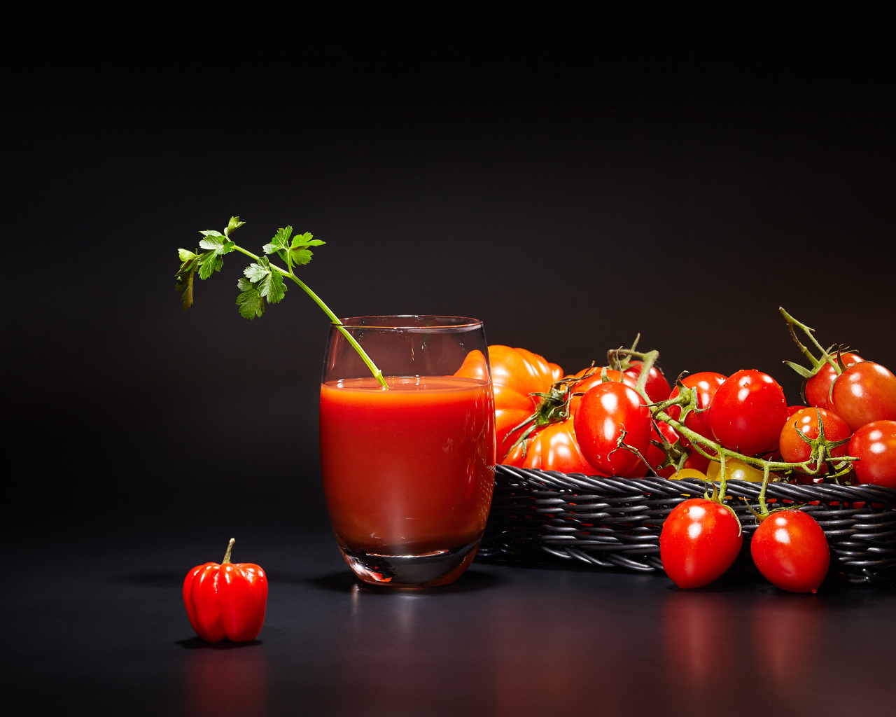 Стакан томатного сока на столе с помидорами