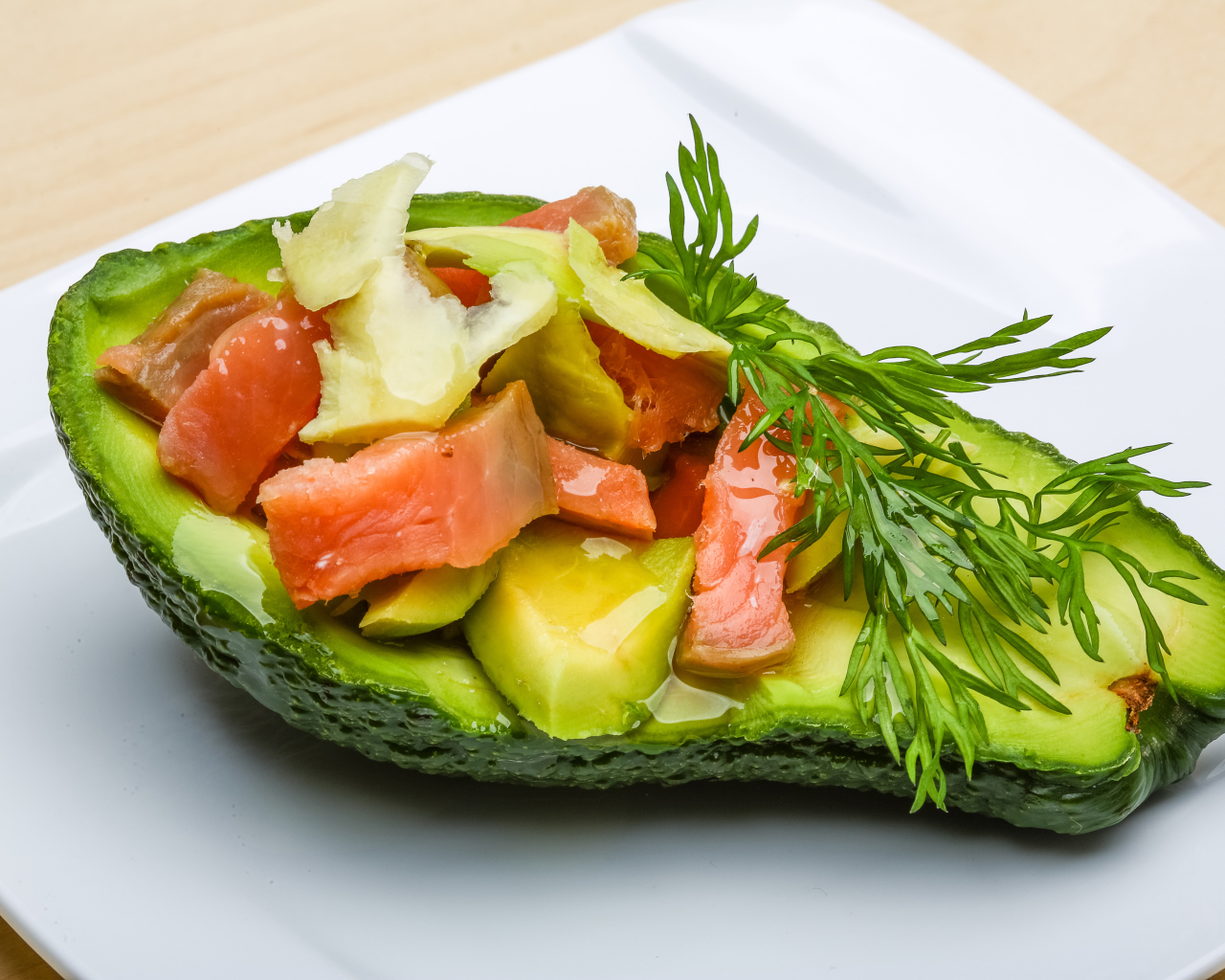 Авокадо с салатом из красной рыбы на белой тарелке