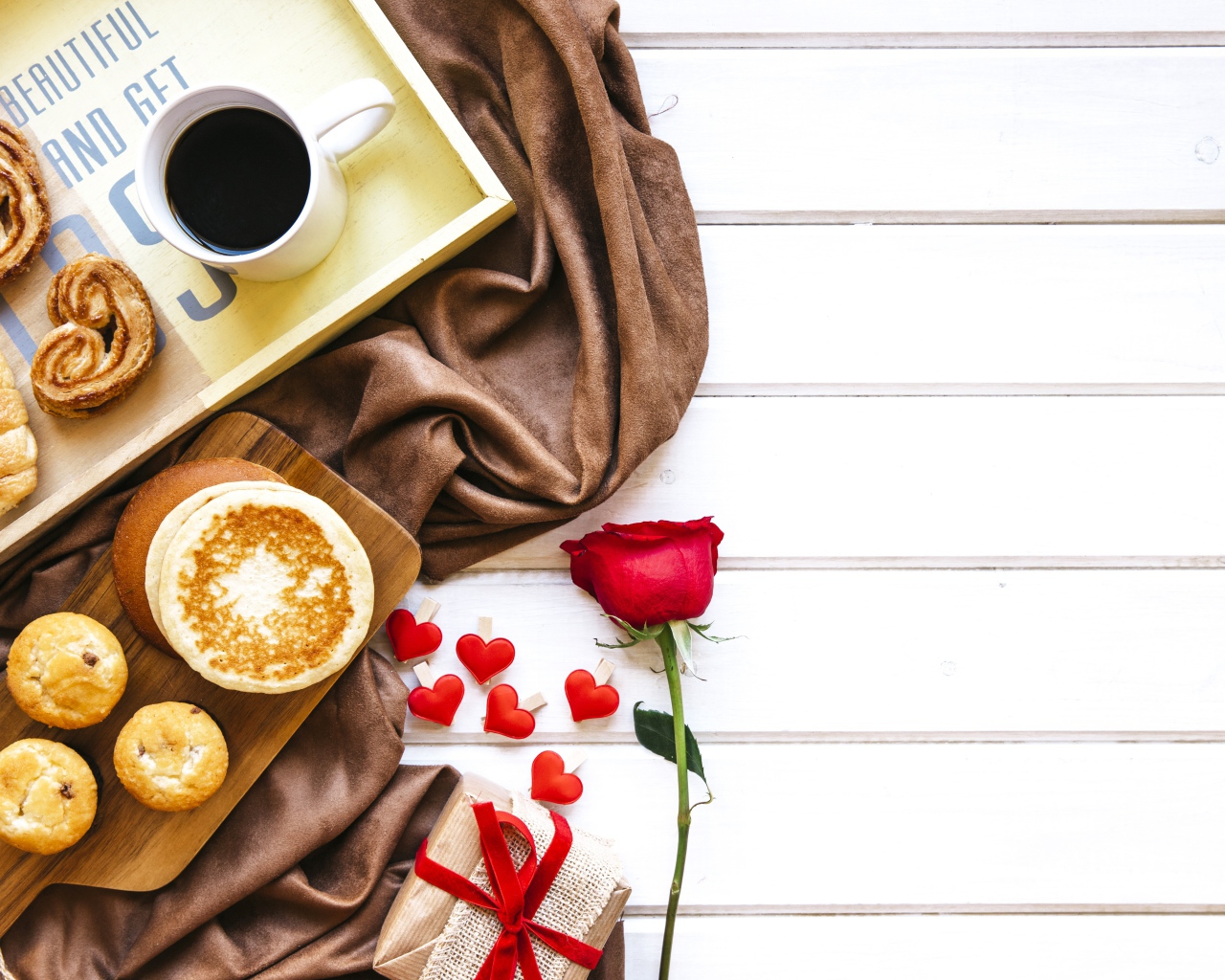 Выпечка на столе с кофе, подарком и красной розой