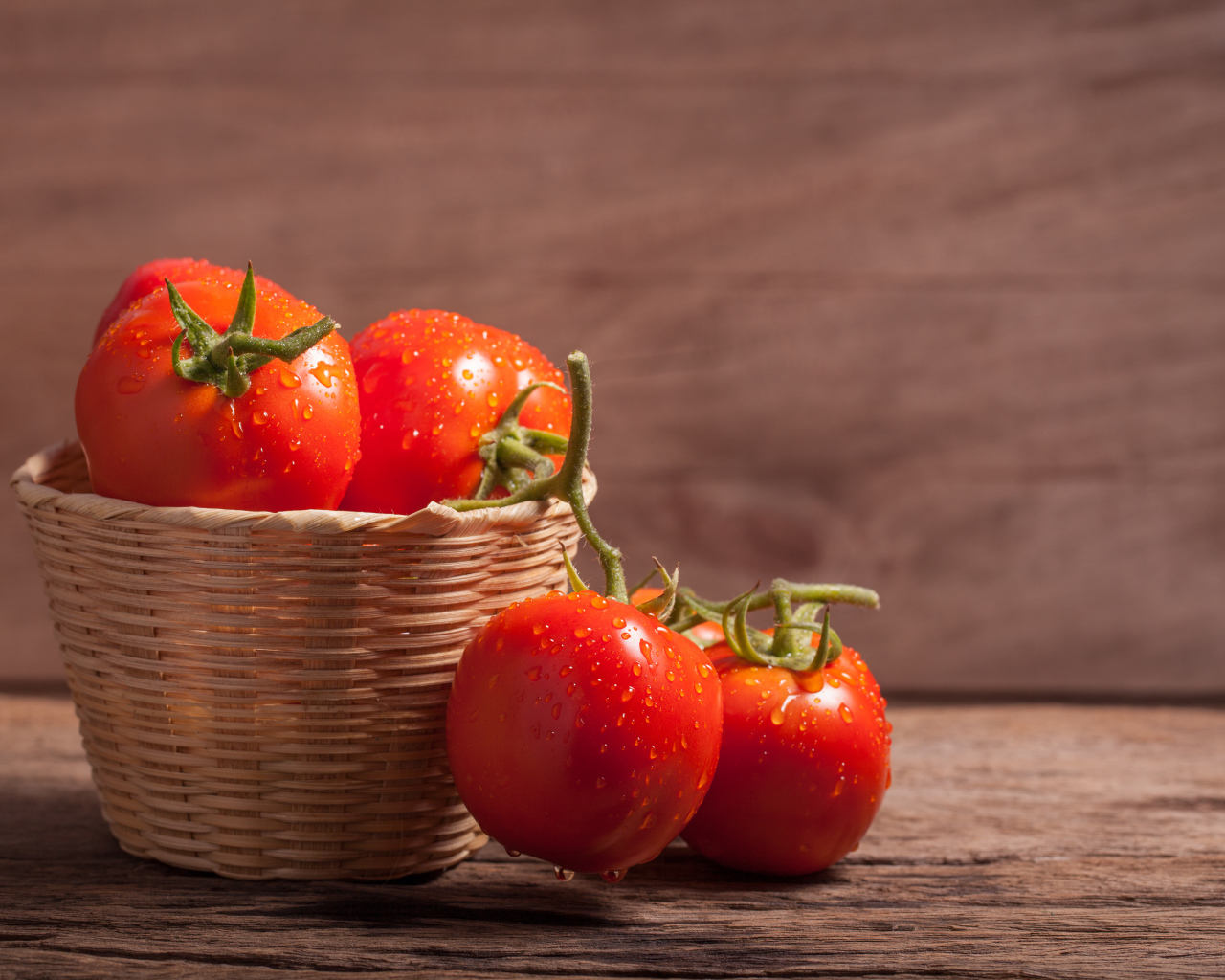 Красивые красные мокрые помидоры в корзине на столе 