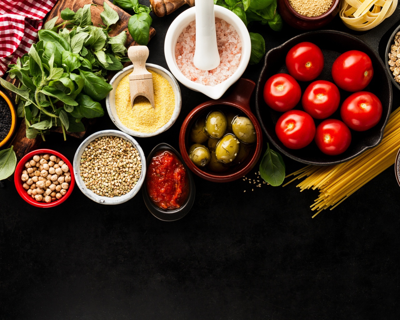 Крупы на столе с зеленью, помидорами, оливками и спагетти