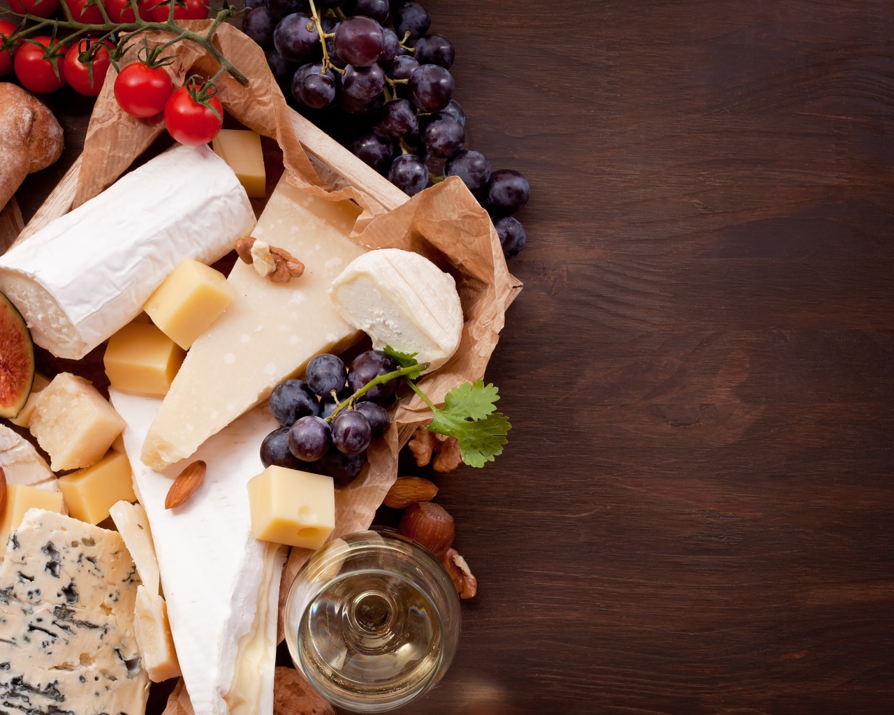 Сыр на столе с виноградом, инжиром и помидорами
