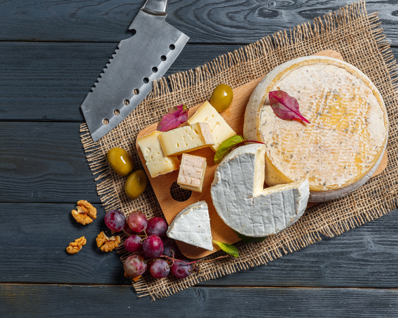 Сыр с плесенью на столе с орехами и виноградом 