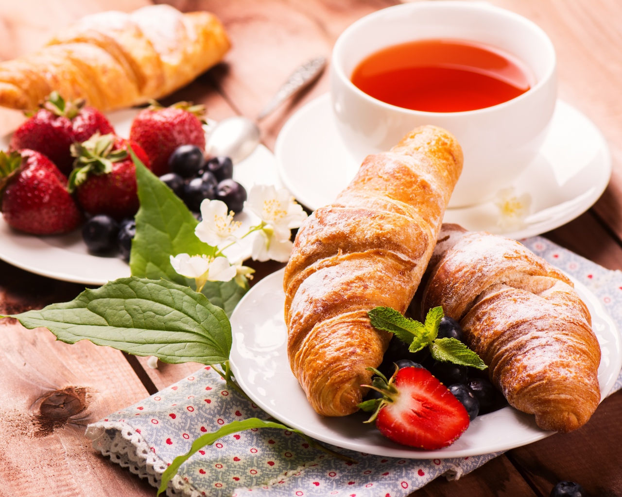 Круассаны на столе с ягодами и чашкой чая