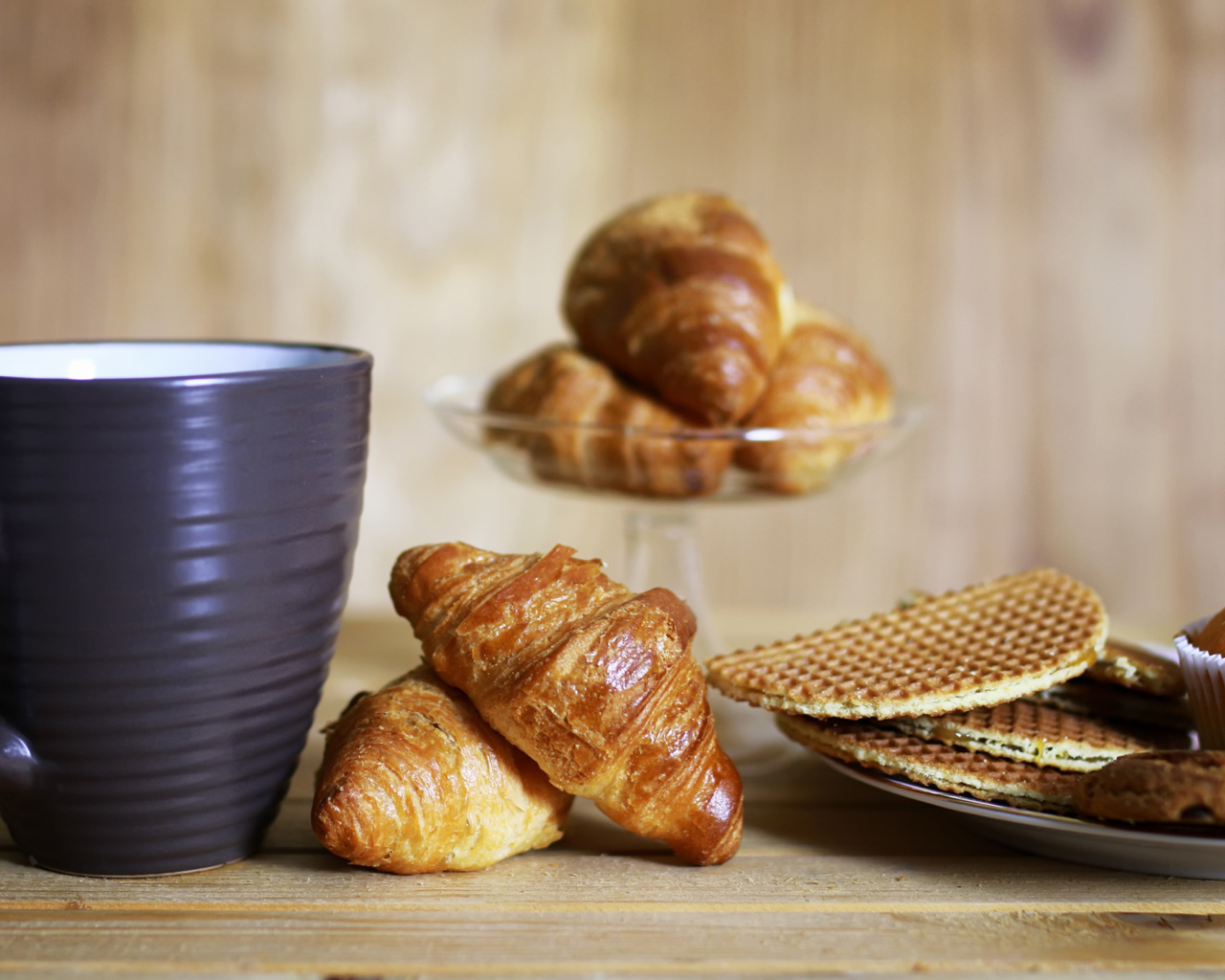 Чашка на столе с круассанами и вафлями 