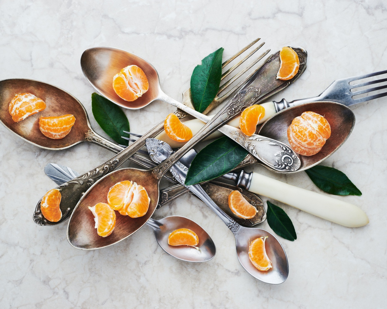 Столовые приборы на столе с дольками мандарина