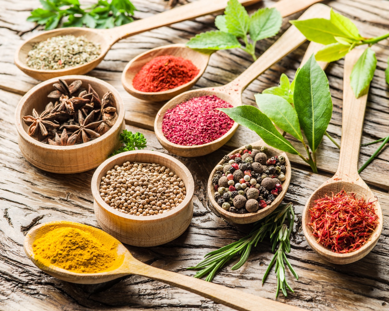 Разные специи в деревянных ложках на столе 