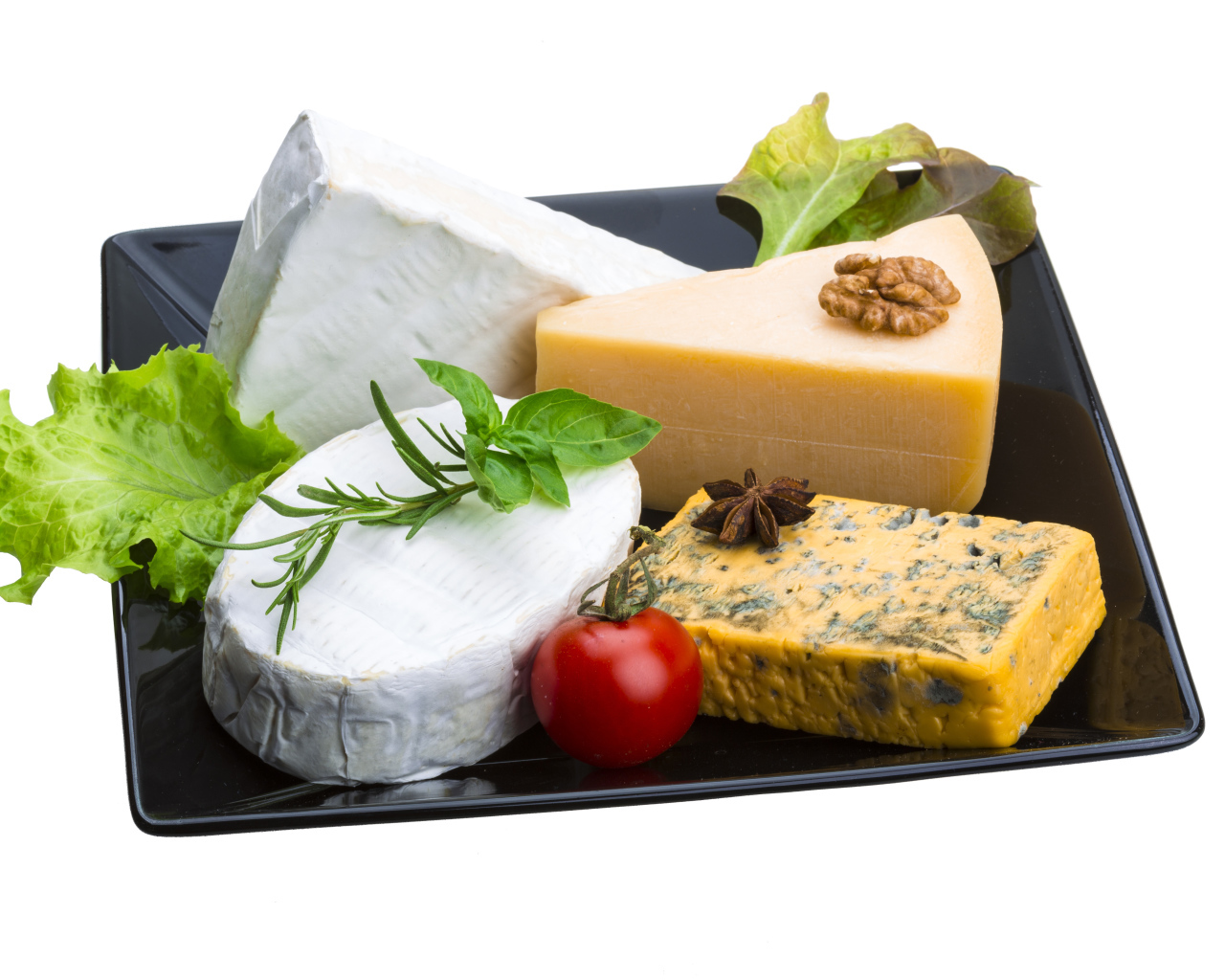 Разные виды сыра на черной тарелке на белом фоне
