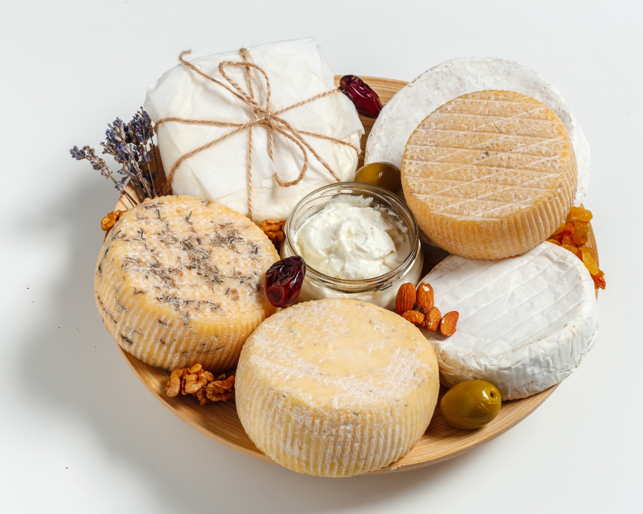 Разные виды сыра на тарелке с орехами на сером фоне