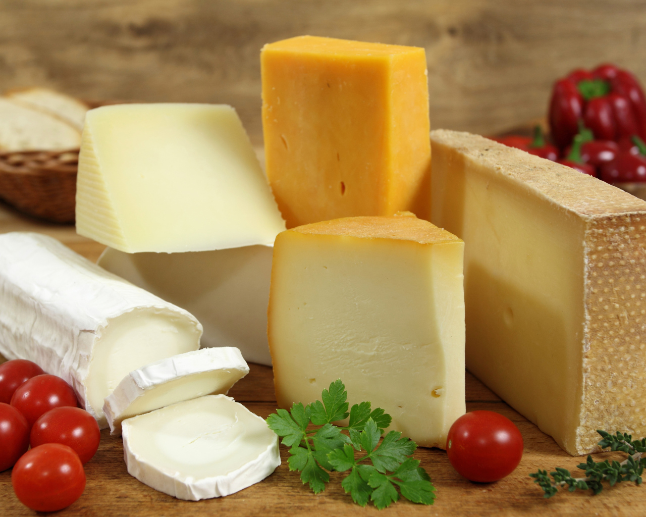 Разные виды твердого сыра на столе с помидорами и петрушкой