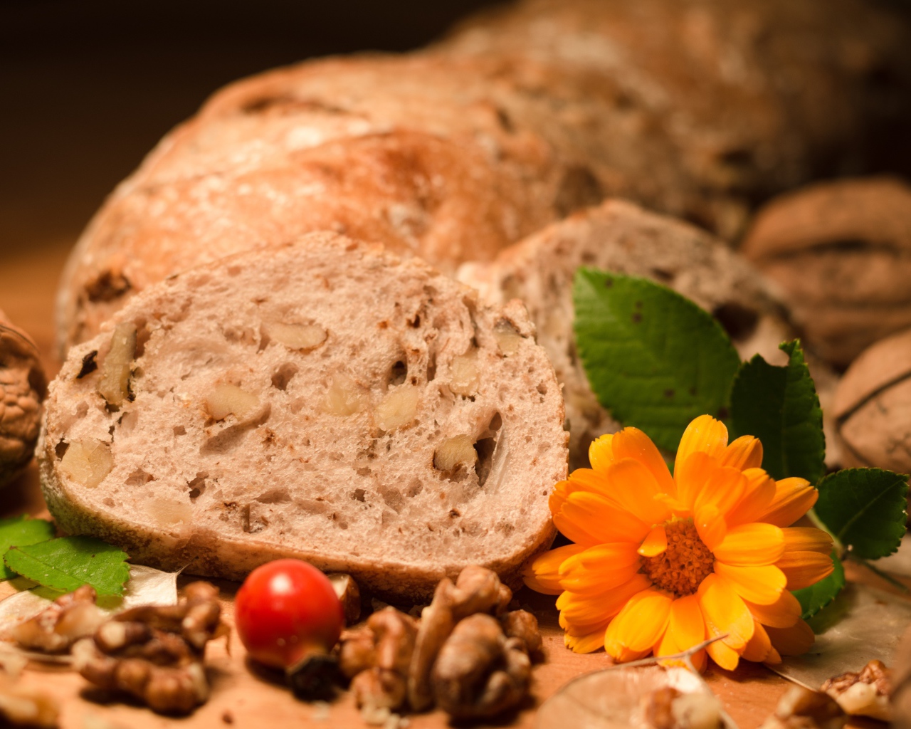 Свежий хлеб с грецкими орехами и цветами календулы на столе