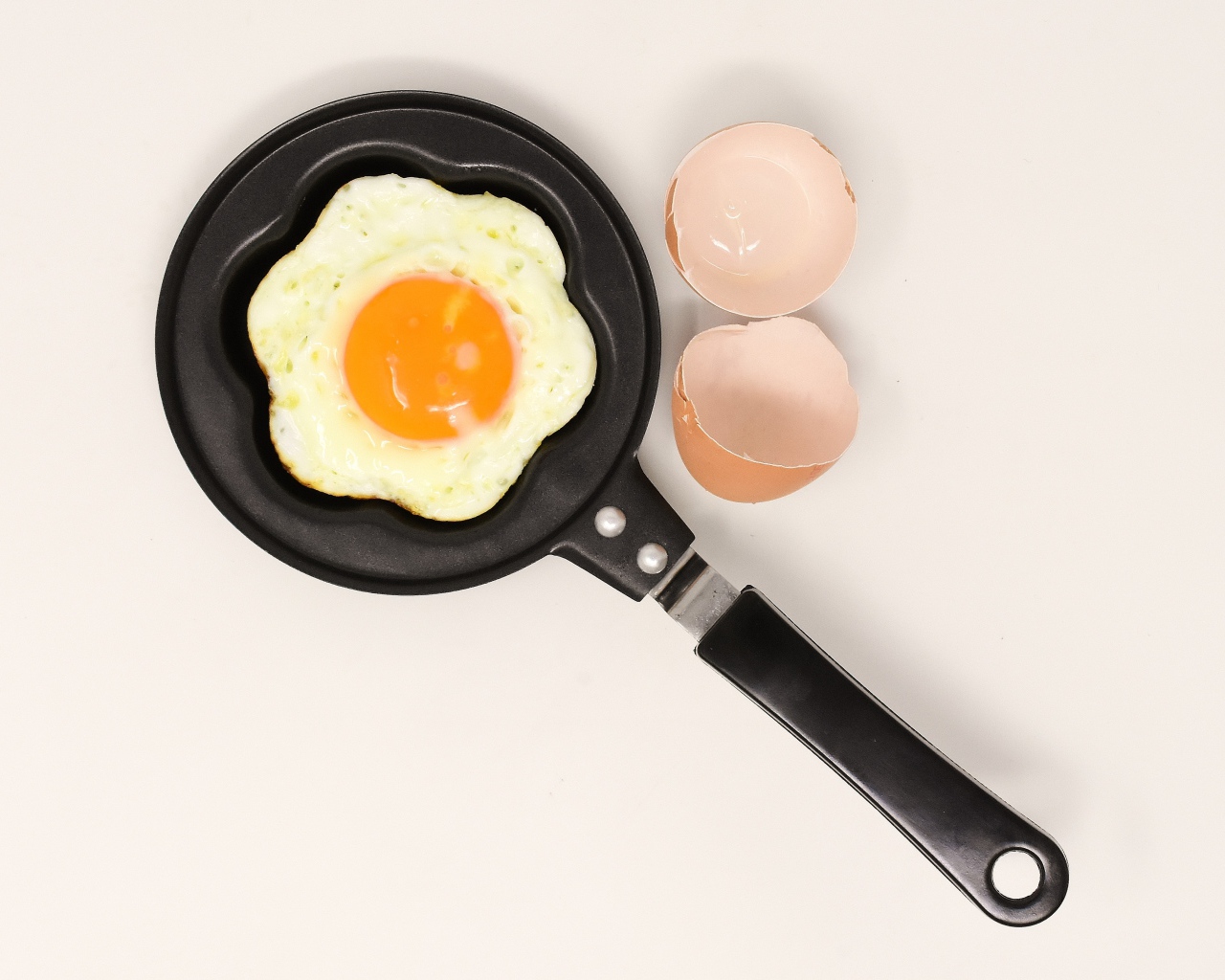 Яичница на сковороде на сером фоне со скорлупой